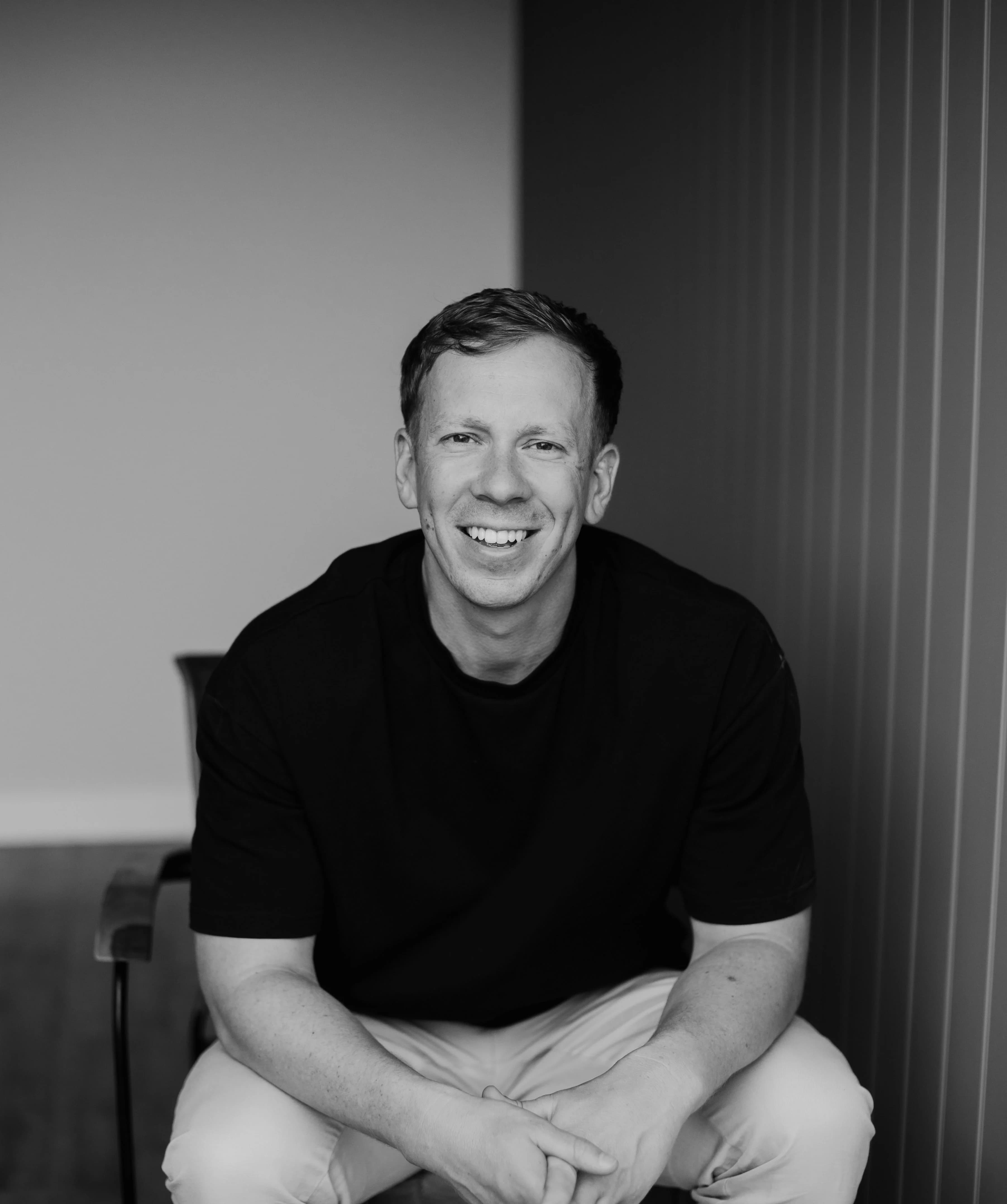Shaun of Shaun Young Films, sitting and smiling, in a black and white portrait