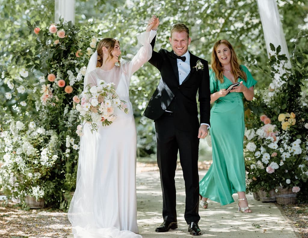 A couple walking back up the aisle, their celebrant behind them